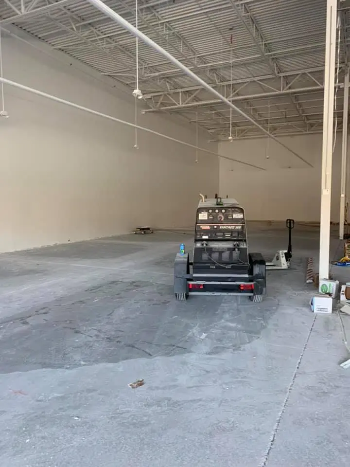 A finished construction site with freshly completed drywall, with a forklift and compressor in the background.